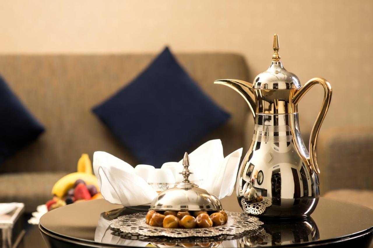 Al Ghufran Safwah Hotel Makkah Mekka Exteriör bild The photo features a beautifully arranged setting. There is a shiny, ornate coffee pot made of metal, often associated with traditional Arabic coffee. Next to it is a decorative dish, also metallic, likely used for serving sweets or snacks. The dish 