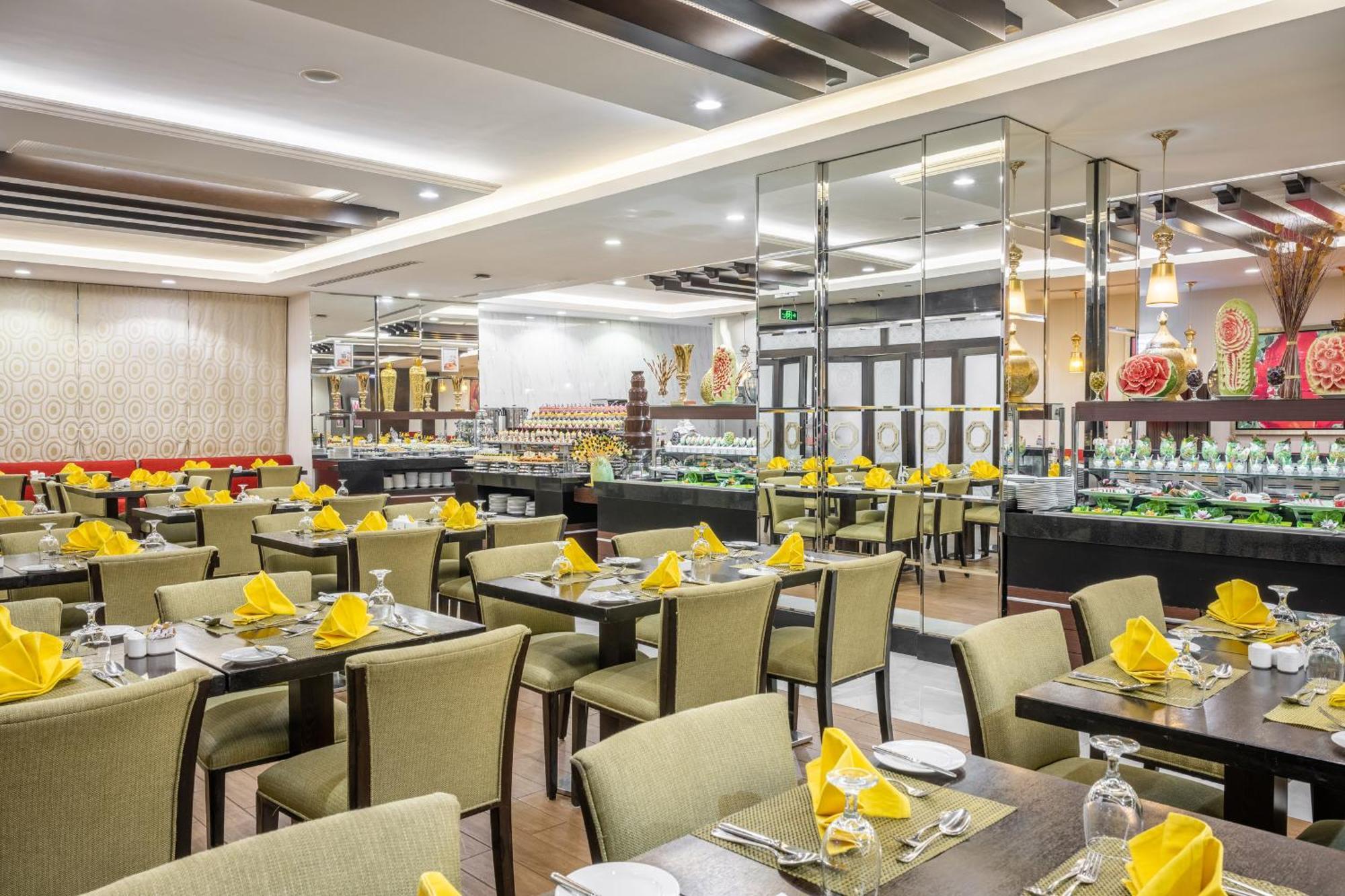 Al Ghufran Safwah Hotel Makkah Mekka Exteriör bild The photo shows an interior of a restaurant. The dining area features several tables covered with green tablecloths, each set with white plates, silverware, and folded yellow napkins. The chairs are also green, complementing the table decor. In the b